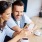 a man and woman sitting at a table and looking at a phone