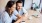 a man and woman sitting at a table and looking at a phone